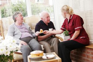 couple senior accompagné par une professionnelle qui lui sert la nourriture